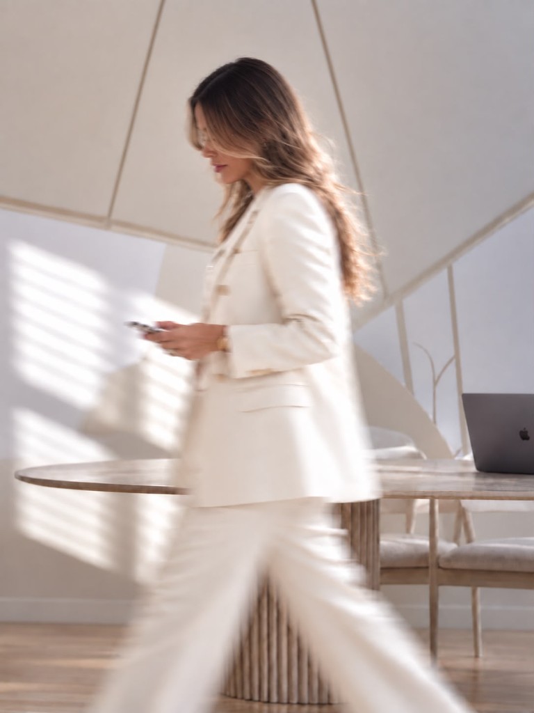 Celeste caminando en un estudio, con blazer blanco