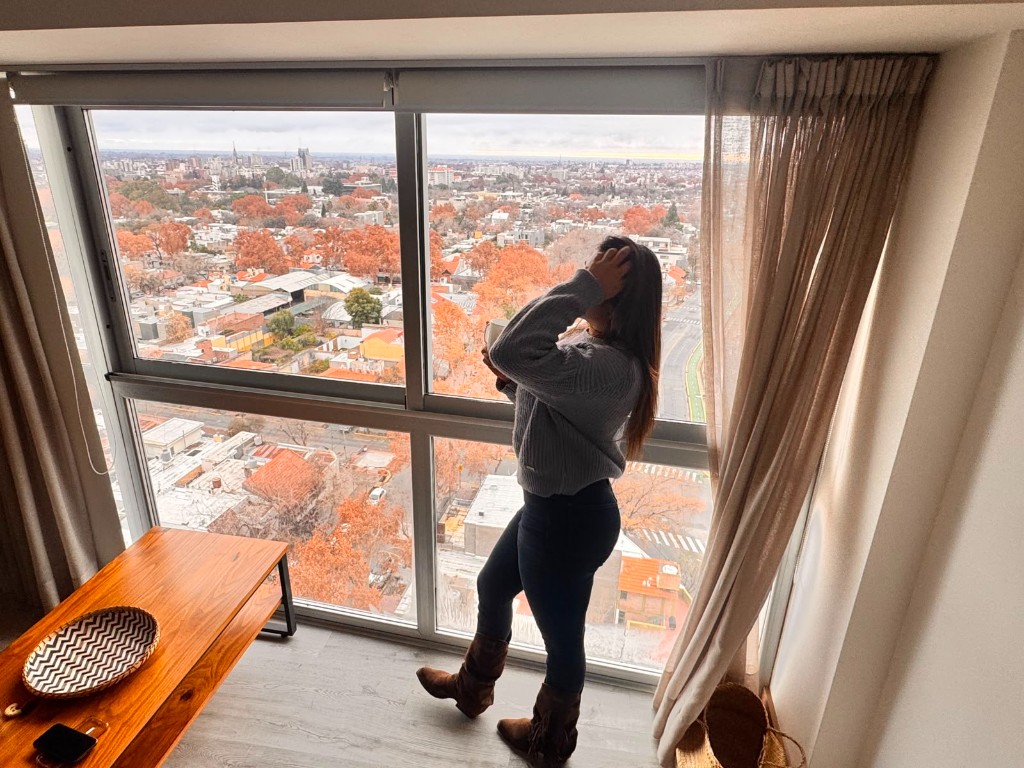 Celeste mirando la ciudad desde una ventana, en un viaje
